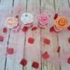 Boîte décorative avec roses de couleur pêche, perles nacrées fuchsia, paillettes et noeud en ruban, idéal pour une touche élégante et colorée.