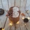 Coco mystique, composition florale dans une noix de coco avec des roses blanches, des roses chocolat, des minis hortensias marron, des perles dorées et des paillettes pour une ambiance magique et élégante.