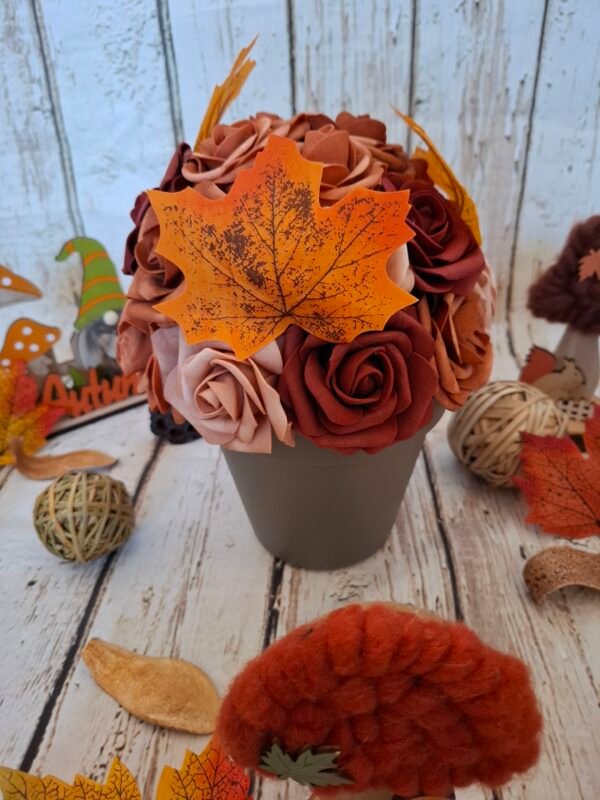 Composition florale Brise d'automne avec des roses aux couleurs automnales, des feuilles d'automne et des teintes orangées, évoquant l'hiver.