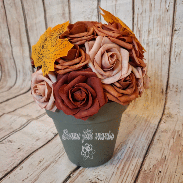 Composition florale "Brise d'automne" avec des roses aux teintes automnales, des feuilles aux couleurs chaleureuses et orangées, évoquant la transition vers l’hiver. Pot personnalisable selon vos envies.