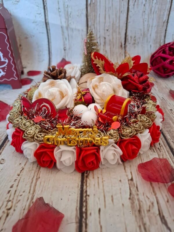 Féérie festive, centre de table avec mousse blanche, sapin doré, pomme de pin, roses blanches, cercles en bois, perles dorées pailletées, fleur rouge, guirlande, traineau, bonbon et canne à sucre pour Noël.