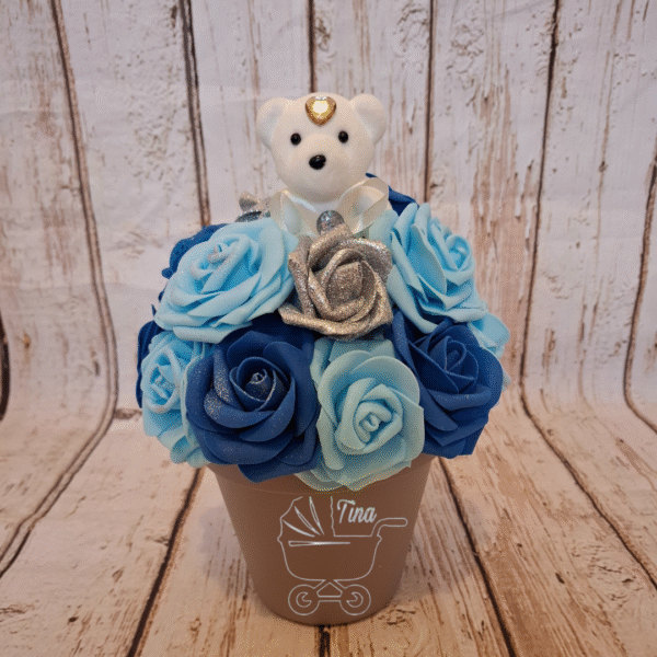 Composition florale Calin bleu avec un ourson blanc et des roses pailletées argentées dans des tons de bleu personnalisation de pot