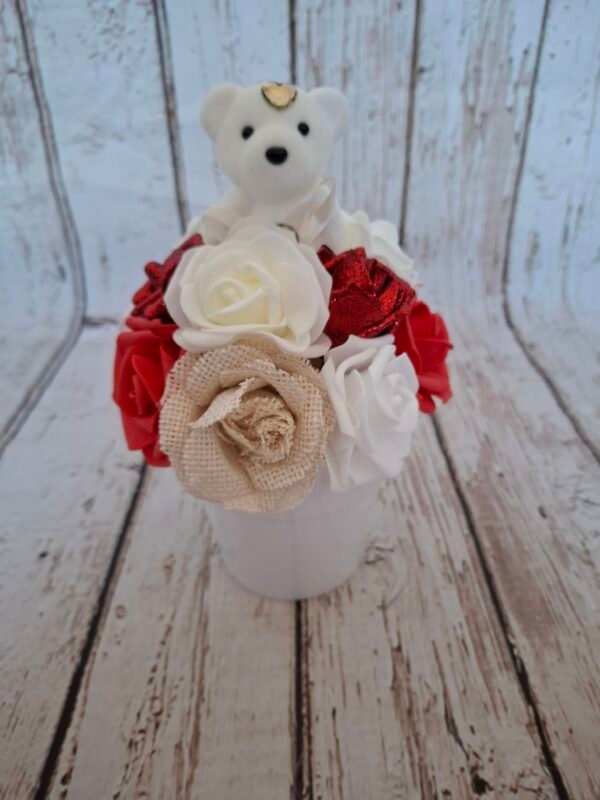 Composition florale Câlin Scintillant avec rose jute blanches, roses rouges claires, roses pailletées rouges, roses crèmes et ourson blanc.