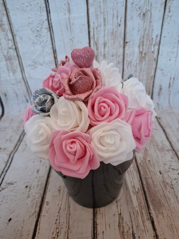 Pot cœur étoilé avec des roses blanches, roses foncées, roses pailletées rose et argent, et un cœur pailleté rose, création florale élégante et romantique.