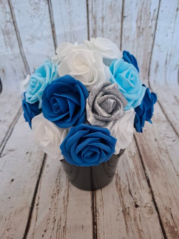 Pot Reflets célestes avec des roses blanches, roses bleues foncées, roses bleues claires et roses pailletées argentées, création florale élégante aux nuances célestes.