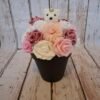 Composition florale Tendre Ourson avec un ourson blanc, des roses pailletées rose, des hortensias rosés, des roses blanches, des roses claires et des roses strass rose foncé.