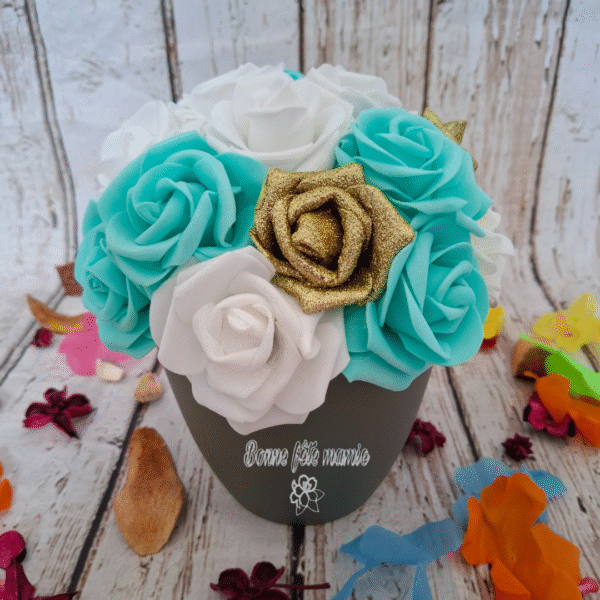 Composition florale Rêve en turquoise avec des roses dorées pailletées, turquoises, blanches et crèmes, avec personnalisation du pot.