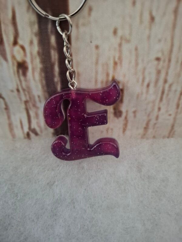 accessoire-personnalisé-créatif-élégant-paillettes-lettres-alphabet-design-003 Lettre E en résine artisanale violette, décorée de paillettes scintillantes, idéale pour un porte-clés élégant.