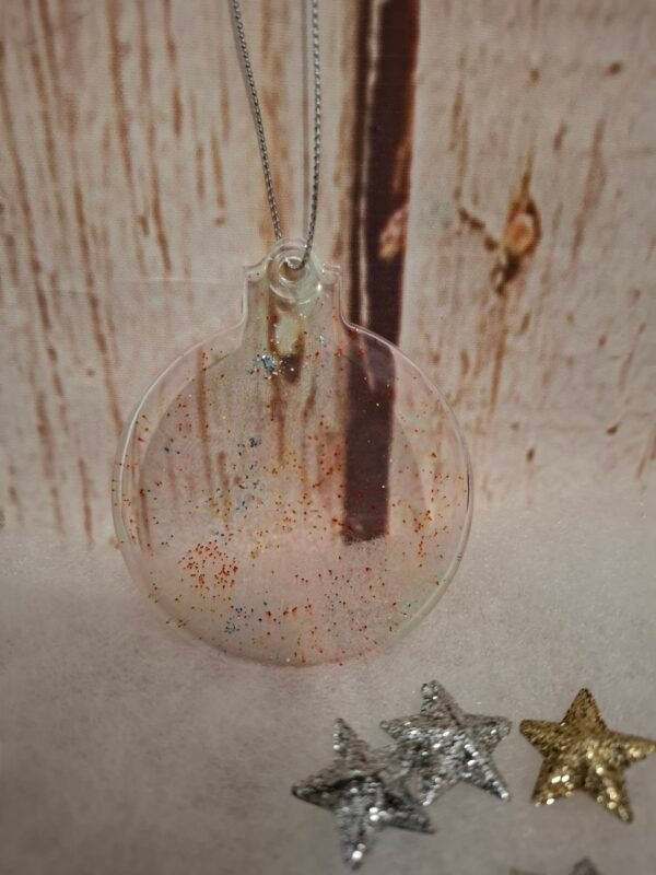 artisanat-boule-transparence-paillettes-personnalisation-001 Boule plate transparente en résine, décorée de paillettes colorées pour un effet lumineux et féerique.