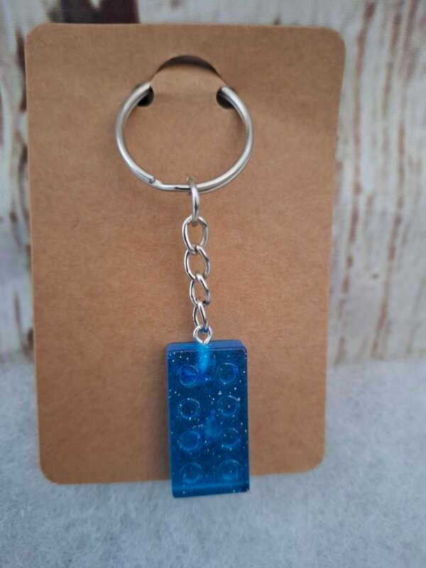 Porte-clés artisanal “Rectangle Magique” en résine colorée, décoré de points lumineux et paillettes, compact (2,9 x 1,5 cm) pour se glisser partout avec style.