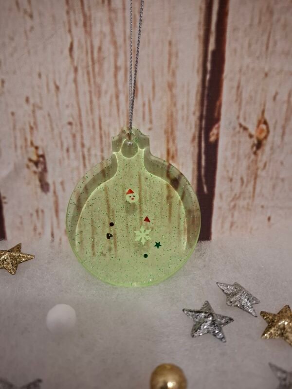 Ornement vert en résine sublimé de paillettes brillantes, imaginé pour l’esprit de fête et prêt à accompagner un joli présent sous le sapin.