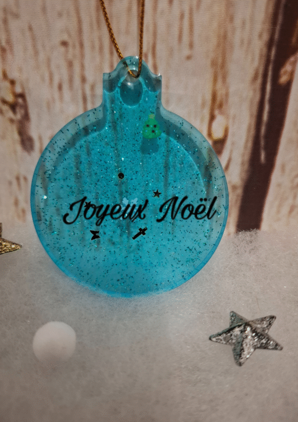 personnalisation-decoration-fetes-ornement-lumineux-flocons-charm-figurine-atelier-artisanat-002 Création artisanale : boule plate bleue avec petits éléments de Noël et paillettes scintillantes.