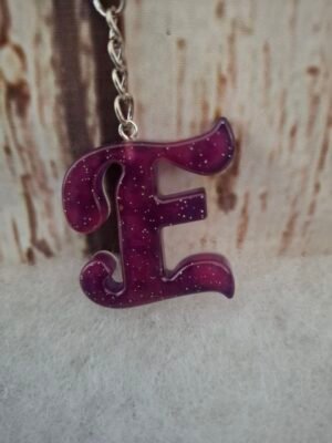 Lettre E en résine artisanale violette, décorée de paillettes scintillantes, idéale pour un porte-clés élégant.