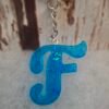 porte-cles-F-resine-artisanale-deco-originale-unique-001 Porte-clés F en résine bleue, décoré de paillettes scintillantes, idéal pour personnaliser sacs et trousseaux avec élégance.