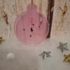 Création unique en résine : boule plate rose avec ornements de fête et éclats brillants.