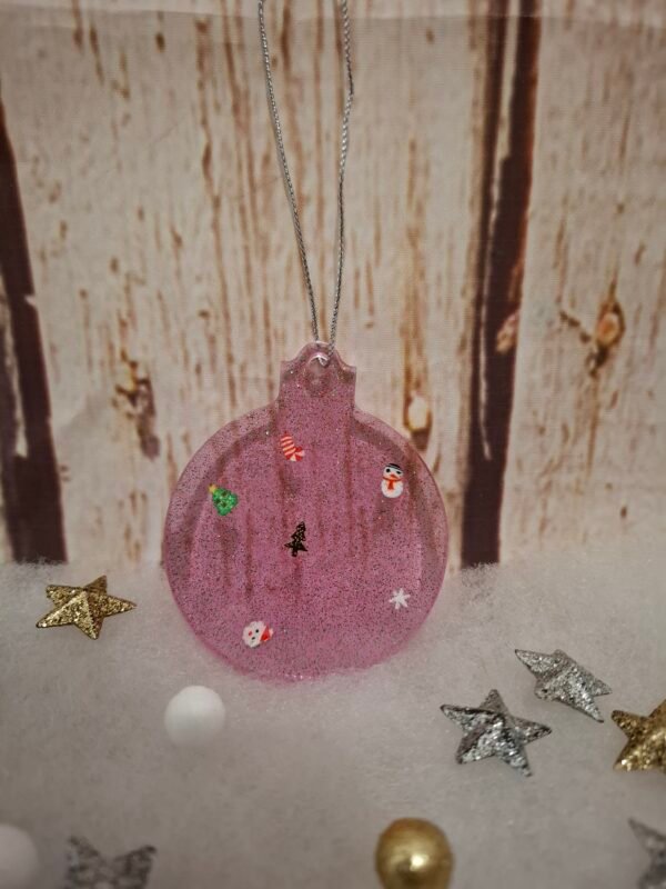 timaiika-floral-surprise-creatrice-suspendu-005 Élément de décoration rose en résine, accompagné de paillettes et miniatures de fête, parfait pour offrir ou exposer.