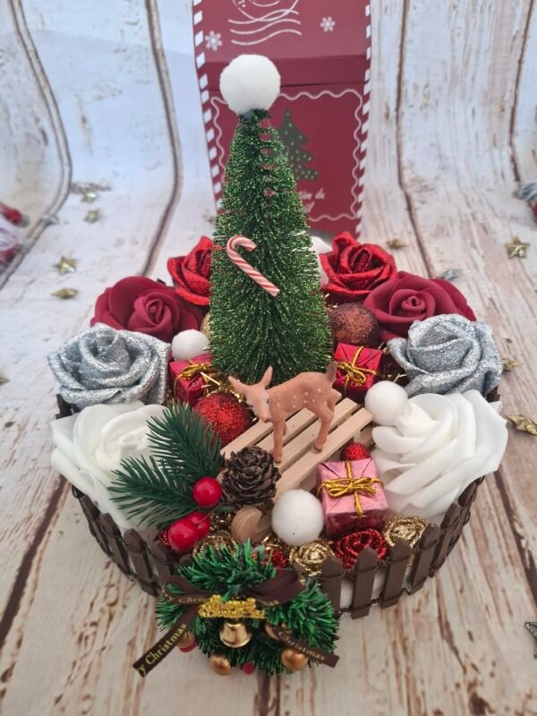 Douce Nuit de Noël, centre de table artisanal avec sapin vert, roses bordeaux et argentées pailletées, mini biche et luge, boules de Noël scintillantes, barrière en bois et décoration hivernale élégante pour vos repas de Noël.