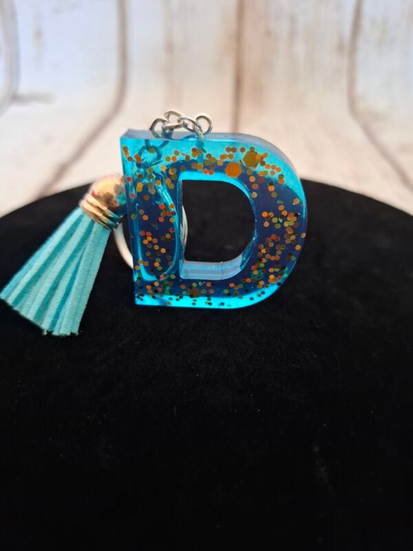 alphabet-hommes-offrir-porteclefs-dorees-pompon-anniversaire-002 Initiale D nuance azur avec inclusions brillantes et pampille textile coordonnée, création manuelle légère et décorative pour accessoires du quotidien