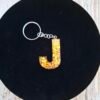 Porte-clés personnalisé lettre J de Jaelys, pièce unique aux nuances rose poudré avec inclusions dorées étincelantes et breloque textile assortie.