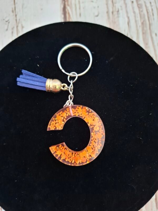 Lettre C Célunéa en résine, décorée de paillettes dorées, pour un détail poétique et élégant sur vos clés.
