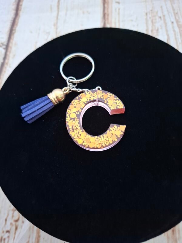 Célunéa, la lettre C en résine artisanale rose, apporte charme et poésie à vos accessoires du quotidien.