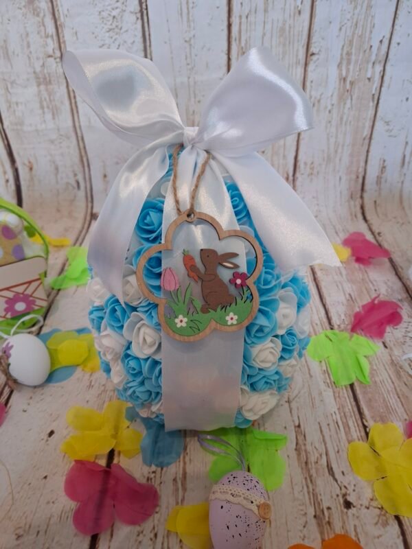 Objet décoratif printanier, paré de fleurs pastel et de mini chocolats, agrémenté d’une figurine tendre en bois.