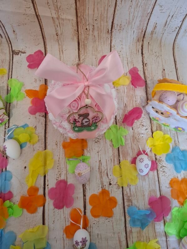 Œuf doux et romantique aux teintes pastel, agrémenté de petites roses délicates, ruban rose élégant et aimants pour maintenir l’ouverture, accompagné d’une mini suspension lapin en bois.