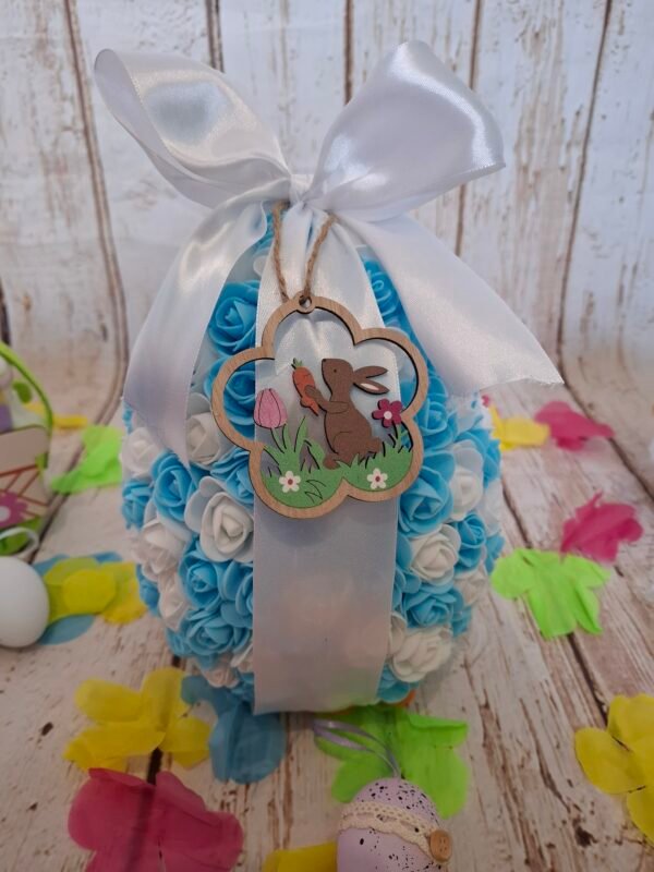 Décoration artisanale raffinée, embellie de petites fleurs et douceurs variées, avec un charmant animal suspendu en bois.