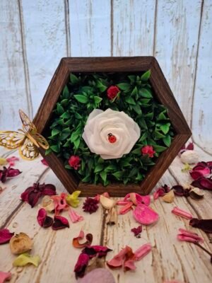 L’hexagone en bois accueille une délicate haie artificielle, créant un écrin élégant pour la composition centrale.