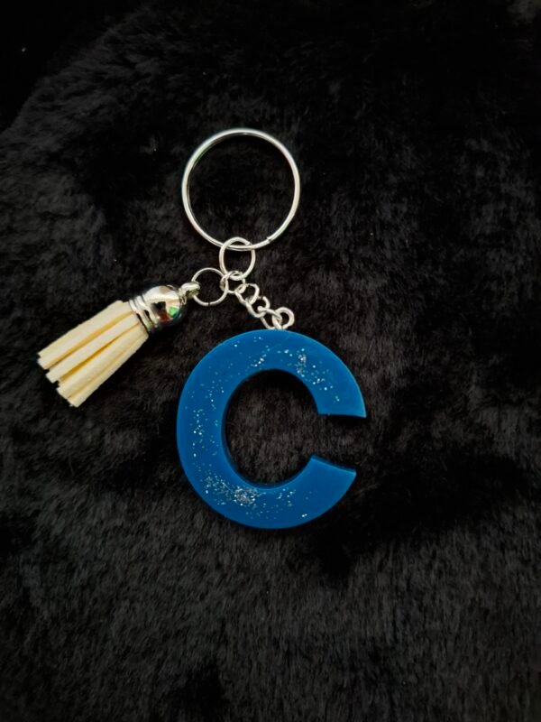 c-cosmynuit-timaiika-portecles-lettre-prenom-resine-bleu-outremer-paillettes-001 C en Cosmynuit, délicatement réalisé avec des touches scintillantes, un petit porte-clés élégant à suspendre sur vos sacs ou trousseaux.