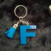 porteclefs-resine-bleu-paillettes-cadeaux-lettres-couleur-f-timaiika-outremer-argentees-001 F en Fynight, lettre en résine délicate, ornée de paillettes scintillantes, montée sur un porte-clés charmant.