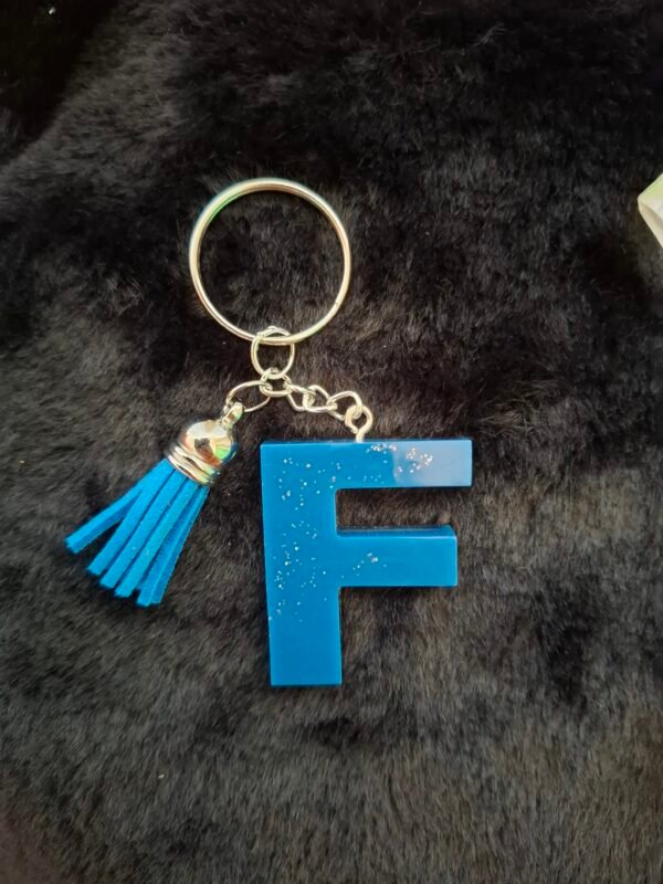porteclefs-resine-bleu-paillettes-cadeaux-lettres-couleur-f-timaiika-outremer-argentees-001 F en Fynight, lettre en résine délicate, ornée de paillettes scintillantes, montée sur un porte-clés charmant.